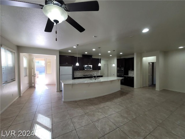 kitchen featuring ceiling fan, stainless steel appliances, tasteful backsplash, a kitchen island with sink, and light tile patterned floors