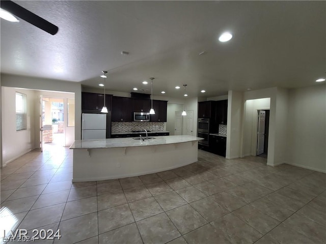 kitchen featuring a kitchen breakfast bar, tasteful backsplash, stainless steel appliances, light tile patterned floors, and an island with sink