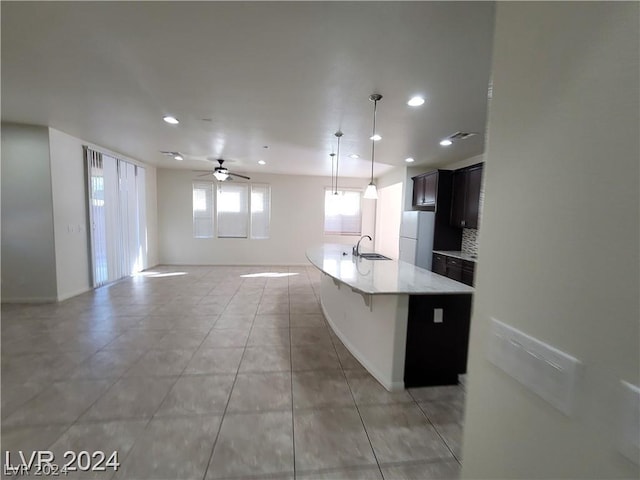 kitchen featuring tasteful backsplash, ceiling fan, sink, white refrigerator, and hanging light fixtures