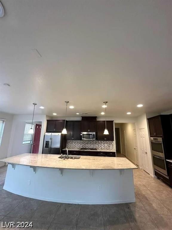 kitchen featuring sink, stainless steel appliances, pendant lighting, a spacious island, and decorative backsplash