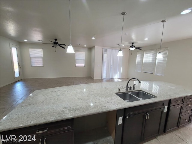 kitchen featuring plenty of natural light, light stone counters, and sink