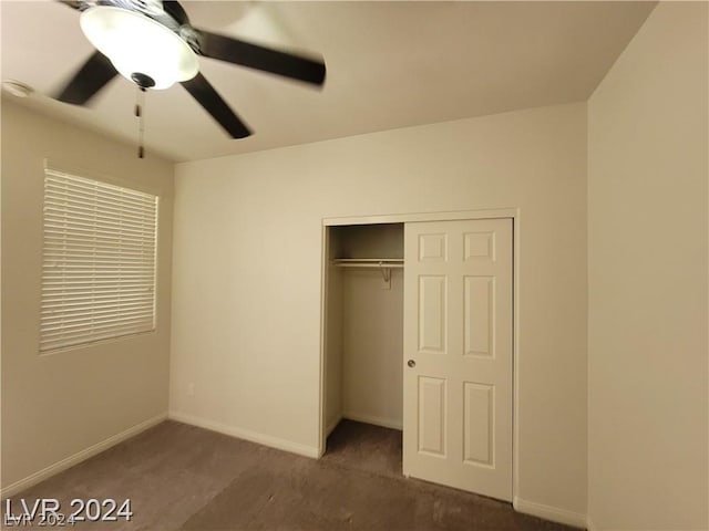 unfurnished bedroom with dark colored carpet, a closet, and ceiling fan