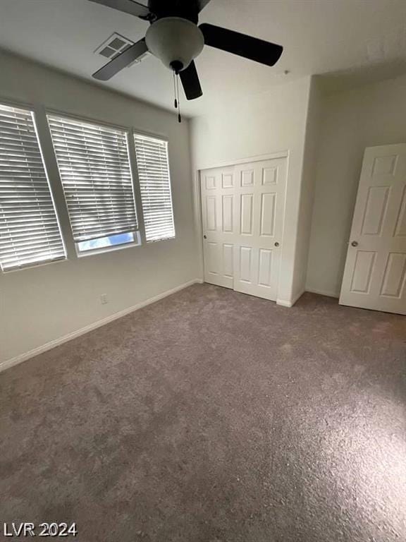 unfurnished bedroom featuring dark colored carpet, a closet, and ceiling fan