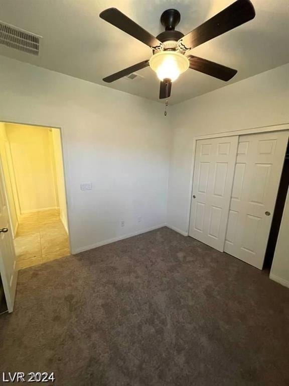 unfurnished bedroom with dark carpet, a closet, and ceiling fan