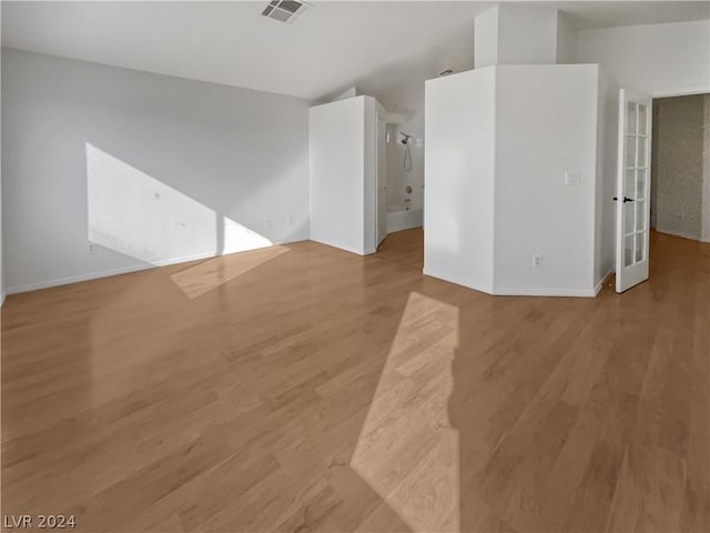 unfurnished room with light hardwood / wood-style floors and lofted ceiling