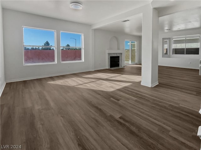 unfurnished living room with dark hardwood / wood-style flooring and a healthy amount of sunlight