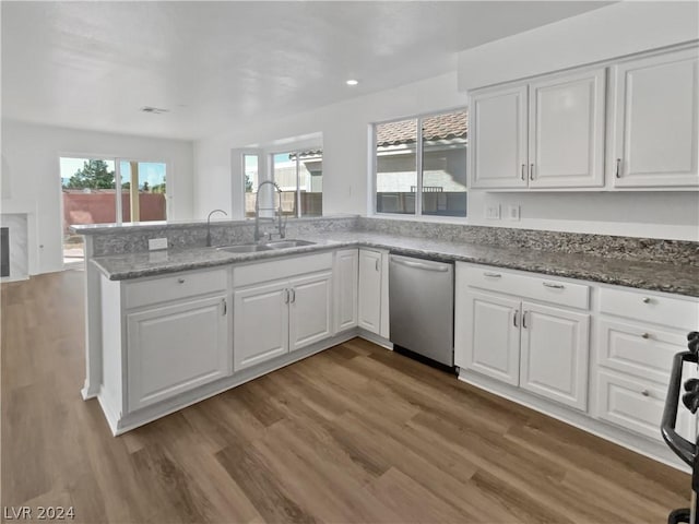 kitchen with stone counters, sink, stainless steel dishwasher, white cabinets, and hardwood / wood-style flooring