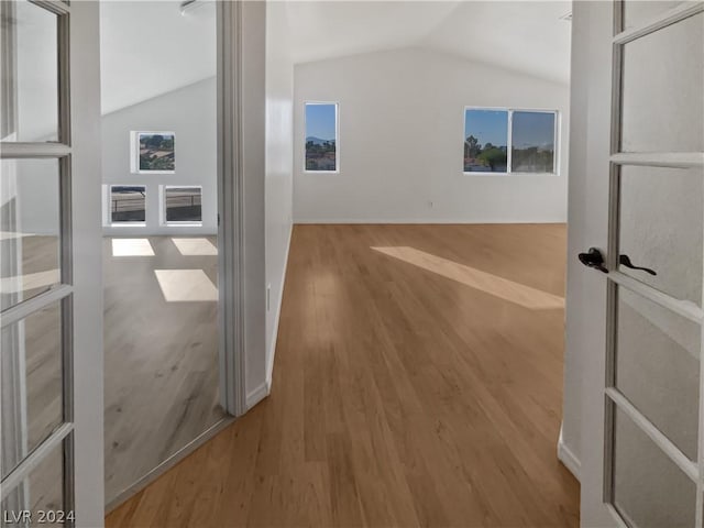 corridor with wood-type flooring and lofted ceiling