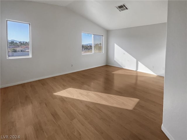 unfurnished room featuring hardwood / wood-style floors and lofted ceiling