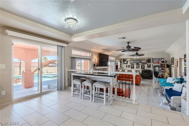 kitchen featuring ceiling fan, light tile patterned floors, a breakfast bar, and lofted ceiling