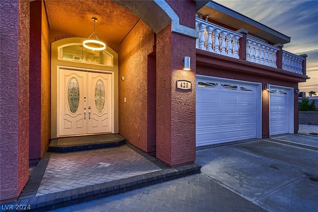 exterior entry at dusk with a garage and a balcony