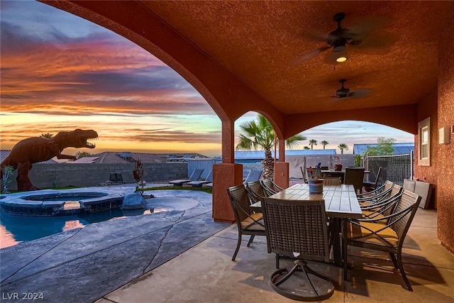 patio terrace at dusk with ceiling fan and a pool with hot tub