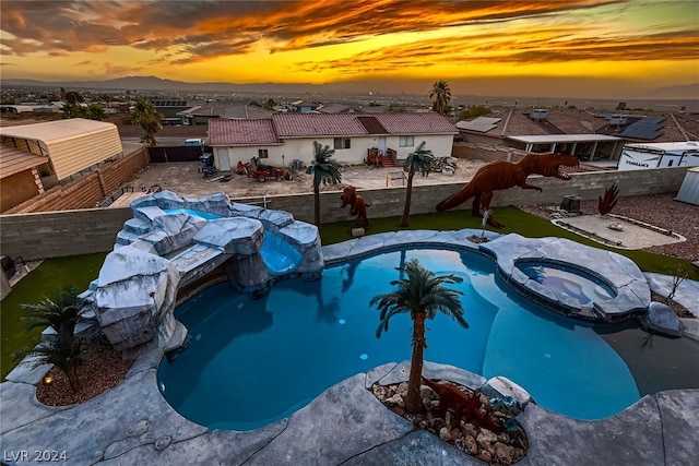 pool at dusk with an in ground hot tub