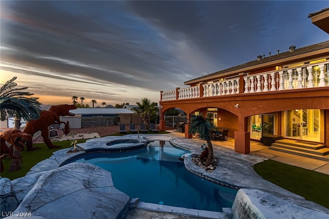 pool at dusk featuring a patio and an in ground hot tub