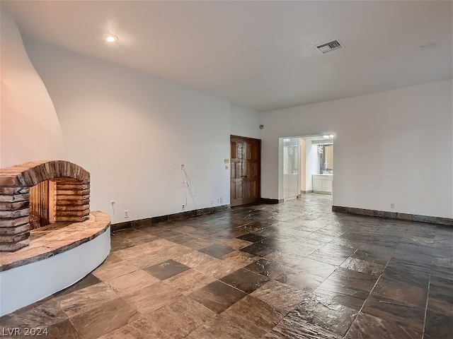 unfurnished living room with visible vents, baseboards, and stone tile flooring