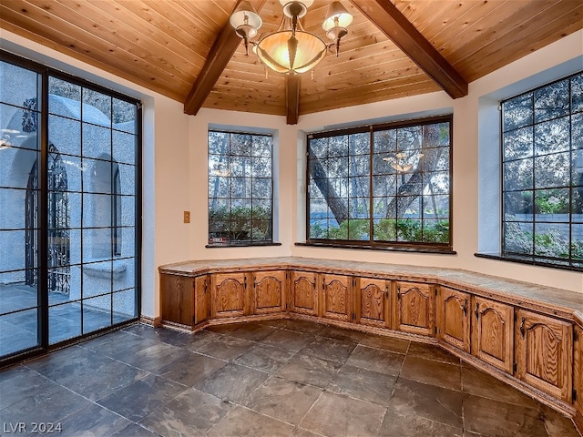 interior space featuring stone tile flooring, wooden ceiling, lofted ceiling with beams, and an inviting chandelier