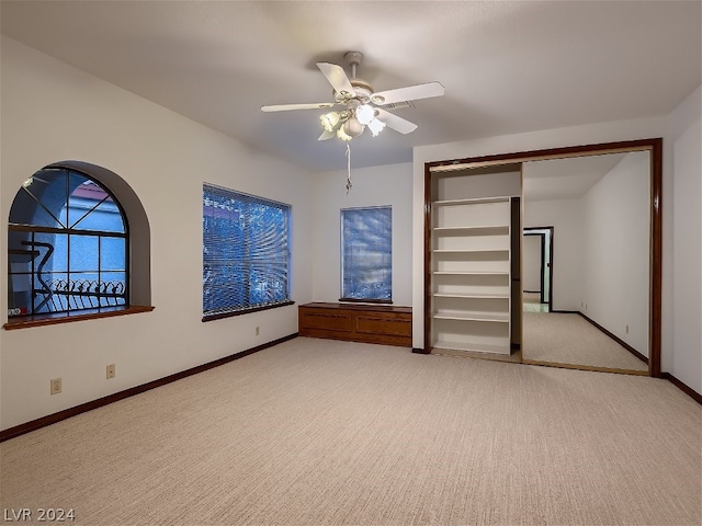 unfurnished bedroom featuring a ceiling fan, baseboards, a closet, and light carpet