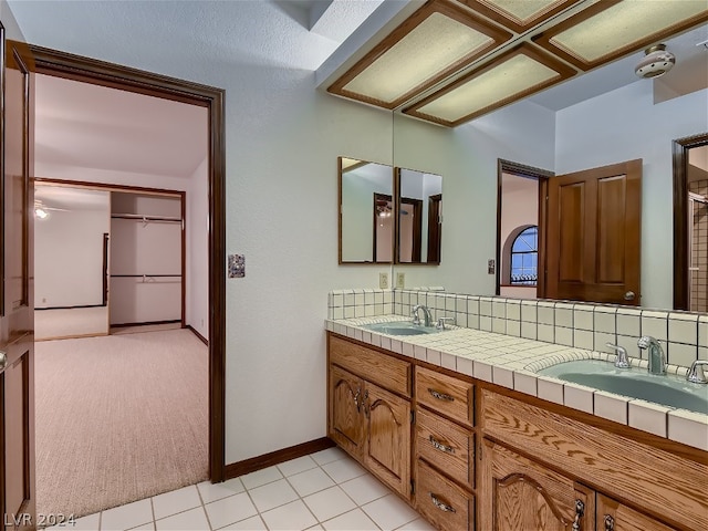 bathroom with tile flooring, vanity with extensive cabinet space, and double sink