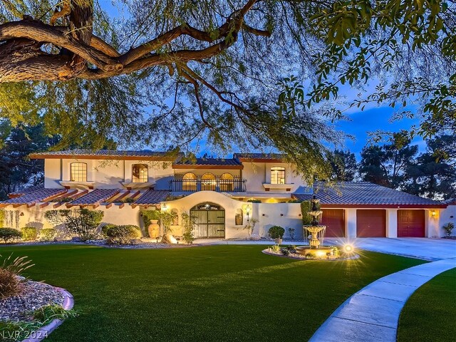 mediterranean / spanish house with a garage and a front lawn