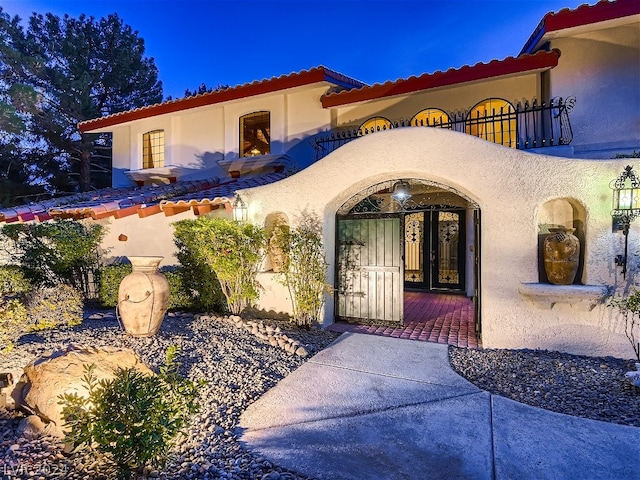 entrance to property featuring stucco siding, french doors, and a balcony