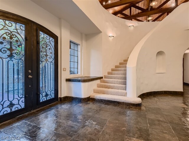 entrance foyer with beamed ceiling, french doors, and dark tile flooring