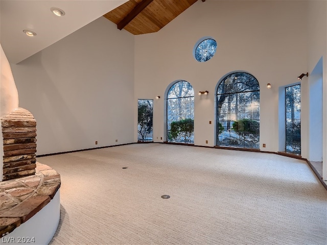 unfurnished living room with wood ceiling, baseboards, and light carpet