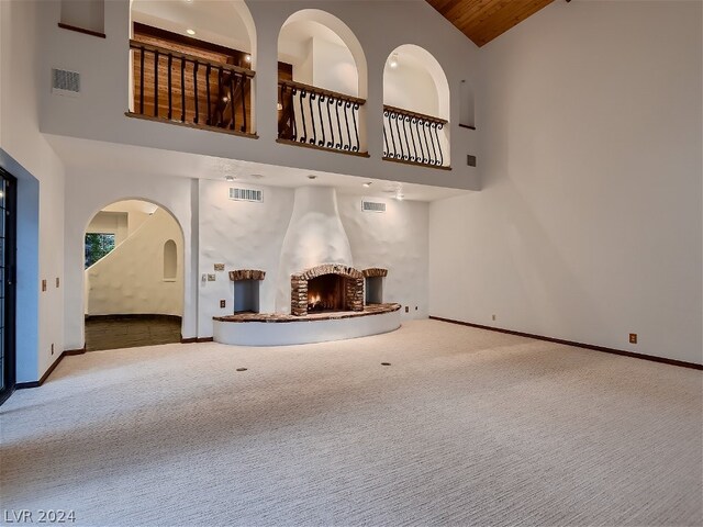 unfurnished living room featuring high vaulted ceiling and carpet flooring