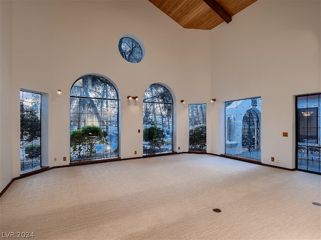 carpeted empty room with wooden ceiling, lofted ceiling with beams, and baseboards