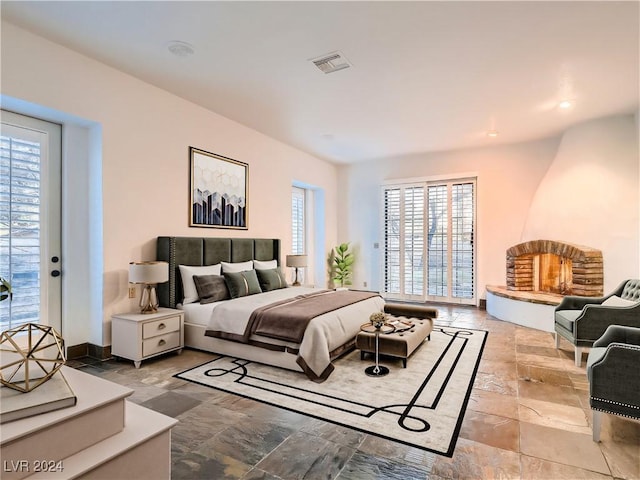 bedroom with stone tile flooring, visible vents, baseboards, and access to outside