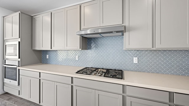 kitchen featuring built in microwave, white cabinets, decorative backsplash, and stainless steel gas stovetop