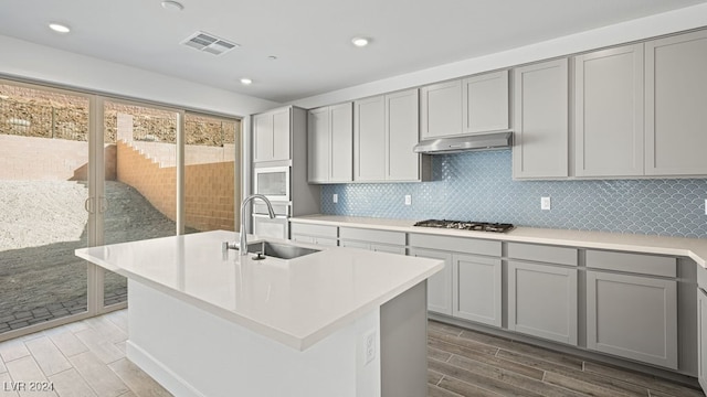 kitchen with a kitchen island with sink, sink, and gray cabinetry