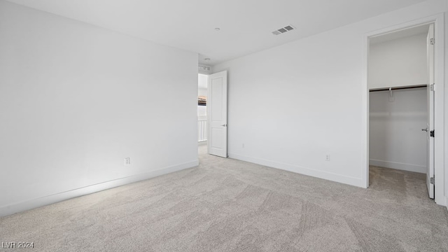 unfurnished bedroom featuring light carpet, a spacious closet, and a closet