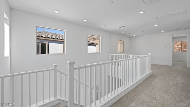 hall featuring light colored carpet and a wealth of natural light