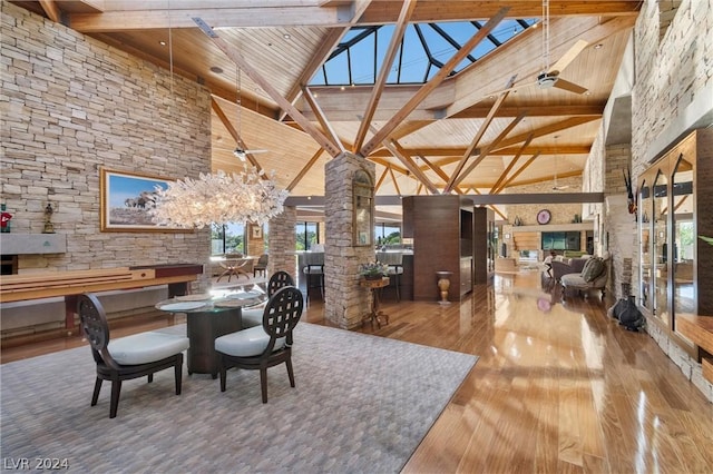 dining space with hardwood / wood-style flooring, beam ceiling, ceiling fan with notable chandelier, wooden ceiling, and ornate columns