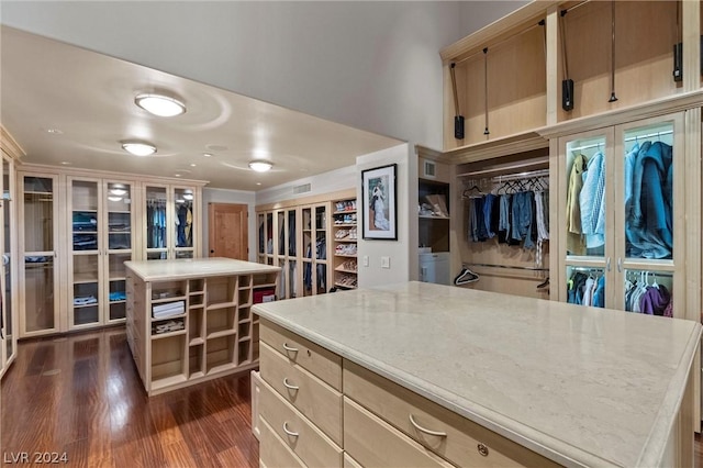 kitchen with washer and clothes dryer, light stone countertops, a kitchen island, dark hardwood / wood-style flooring, and french doors