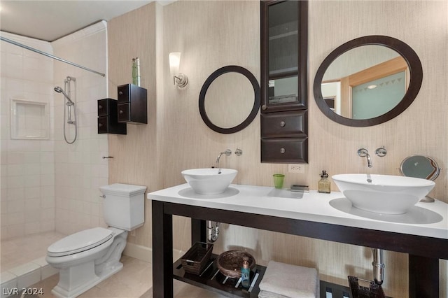 bathroom with a tile shower, sink, tile patterned flooring, and toilet