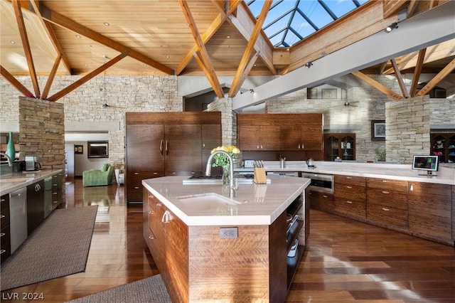 kitchen featuring sink, a high ceiling, a kitchen island with sink, stainless steel dishwasher, and beam ceiling