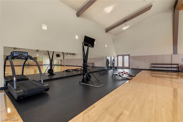 workout area featuring light hardwood / wood-style flooring and high vaulted ceiling