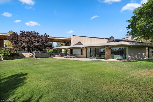 rear view of property featuring a patio and a lawn