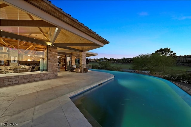 pool at dusk with a patio area