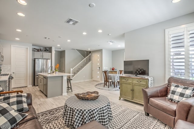 living room featuring sink and light hardwood / wood-style flooring