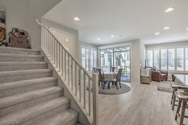 stairs featuring plenty of natural light and hardwood / wood-style flooring