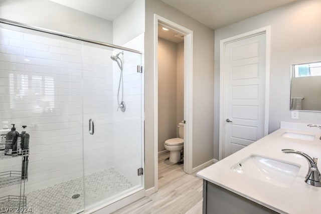 bathroom featuring wood-type flooring, vanity, toilet, and an enclosed shower