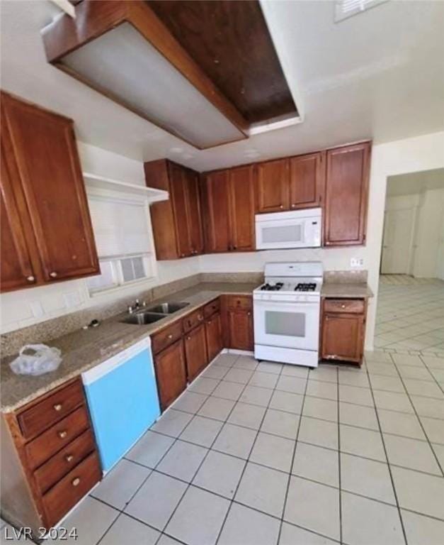 kitchen with white appliances, sink, a raised ceiling, light stone counters, and light tile patterned floors