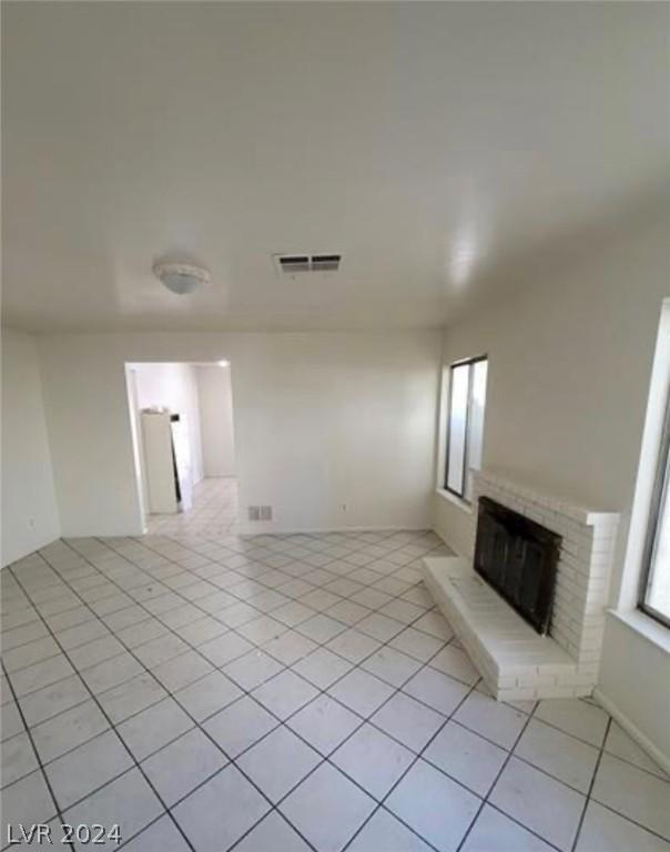 unfurnished living room with light tile patterned floors and a fireplace