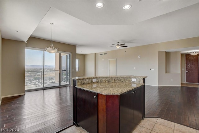 kitchen with hanging light fixtures, light wood-style flooring, open floor plan, ceiling fan, and light stone countertops