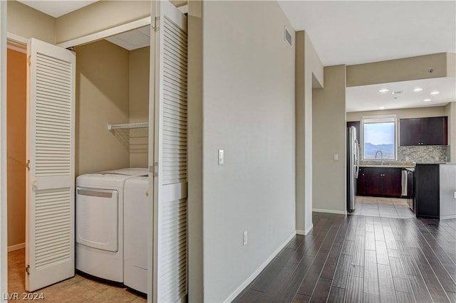 laundry area featuring washing machine and dryer, laundry area, a sink, wood finished floors, and baseboards