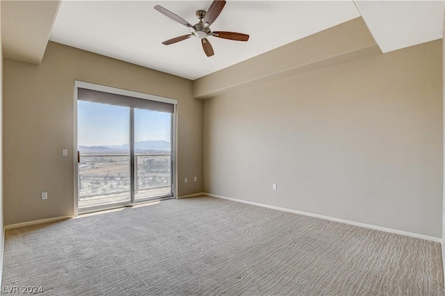 empty room with a ceiling fan, carpet, a mountain view, and baseboards