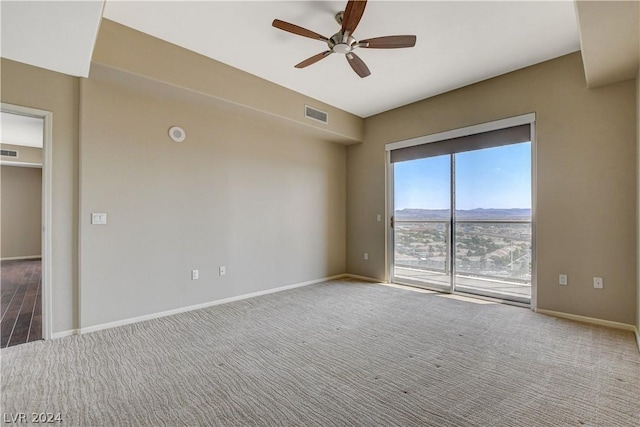 carpeted empty room with a ceiling fan, visible vents, a mountain view, and baseboards