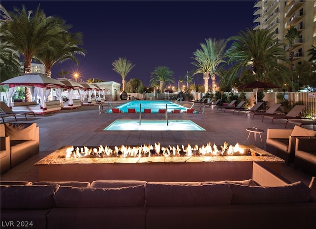 pool at night with a patio, a gazebo, fence, a community pool, and a fire pit